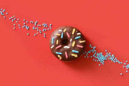 Sweet donut and sprinkles on red backgroundの写真素材