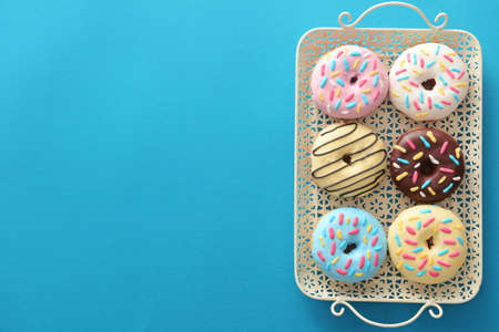 Tray with different sweet donuts on color backgroundの写真素材