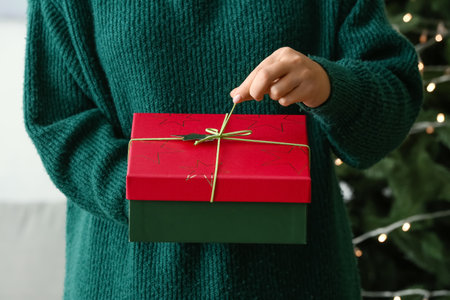 Woman with beautiful Christmas gift box in room, closeupの写真素材