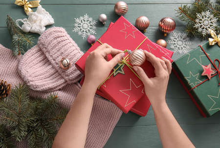 Woman decorating beautiful Christmas gift box on gray wooden backgroundの写真素材