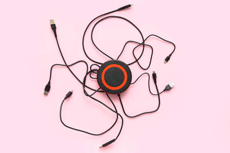 Modern wireless charger pad and cables on color background