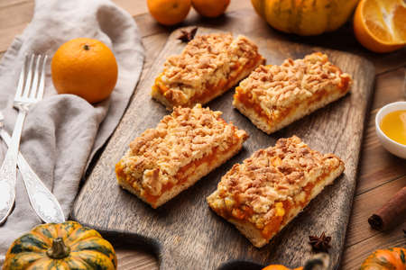 Board with pieces of tasty pumpkin pie on wooden backgroundの写真素材