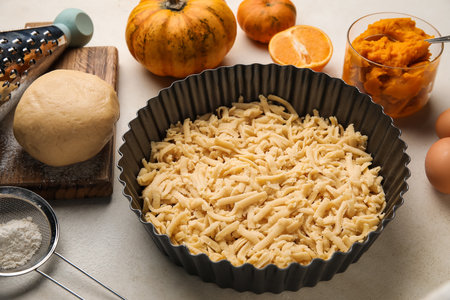 Baking dish with uncooked pumpkin pie and ingredients on white backgroundの写真素材