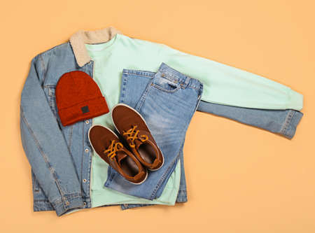 Denim jacket, sweater, jeans, hat and shoes on color backgroundの写真素材