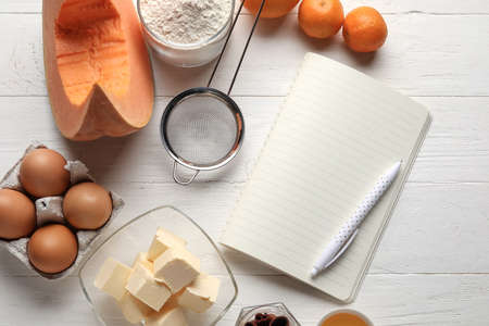 Recipe book and ingredients for pumpkin pie on white wooden backgroundの写真素材