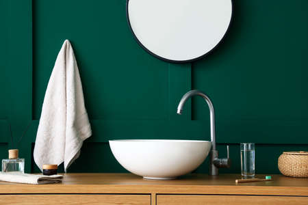 Table with sink and bath supplies near green wallの写真素材