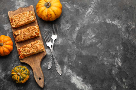 Wooden board with pieces of tasty pumpkin pie on black backgroundの写真素材