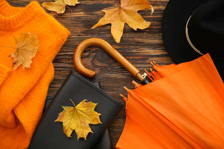 Autumn composition with umbrella, hat, sweater and rubber boots on wooden background, closeupの写真素材