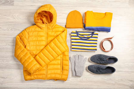 Stylish down jacket and male clothes on light wooden backgroundの写真素材