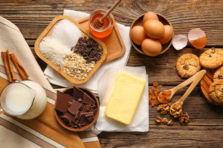 Fresh butter and ingredients for preparing homemade cookies on wooden backgroundの写真素材