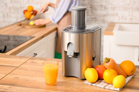 Modern juicer with fresh fruits on table in kitchenの写真素材