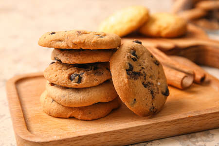 Wooden board with tasty homemade cookies on beige background