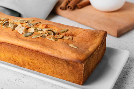 Plate with tasty pumpkin pie on light background