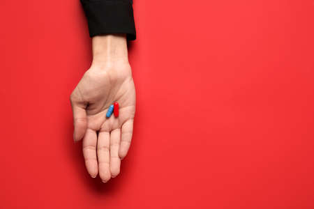 Hand with blue and red pills on color background. concept of choiceの写真素材