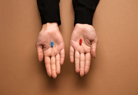 Hands with blue and red pills on color background. concept of choiceの写真素材