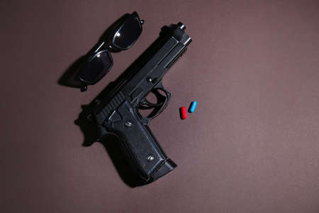 Tinted glasses, gun and pills on color background. Matrix conceptの写真素材
