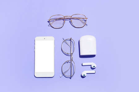 Stylish eyeglasses, mobile phone and earphones on purple backgroundの写真素材