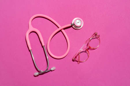 Stylish eyeglasses with stethoscope on pink backgroundの写真素材