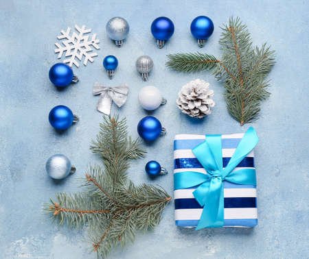 Fir tree branches with beautiful Christmas decor and gift on blue backgroundの写真素材