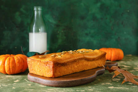 Wooden board with tasty pumpkin pie on green backgroundの写真素材