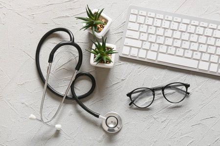 Eyeglasses, computer keyboard, stethoscope and houseplants on gray backgroundの写真素材