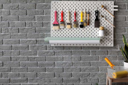 Pegboard with decorator's tools on gray brick wall