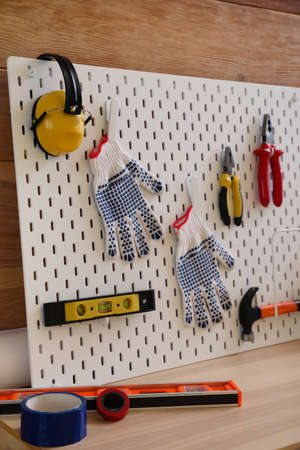 Pegboard with modern tools on desk near wooden wall, closeupの写真素材