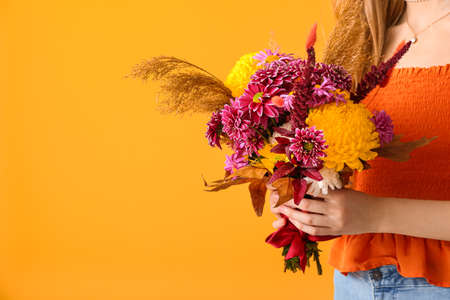 Woman with beautiful autumn bouquet on yellow background, closeupの写真素材