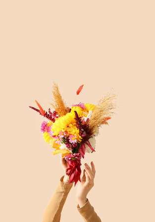 Woman with beautiful autumn bouquet on beige backgroundの写真素材
