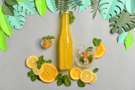 Composition with paper leaves, bottle of fresh soda, fruits and mint on gray backgroundの写真素材