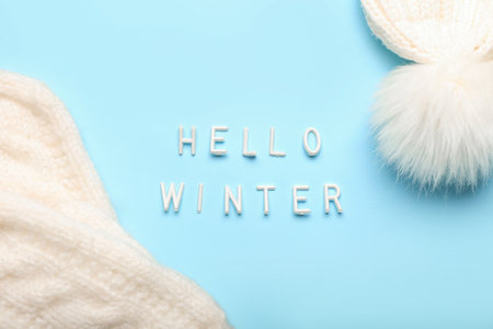 Text HELLO WINTER, knitted mittens and hat on color background, closeupの写真素材