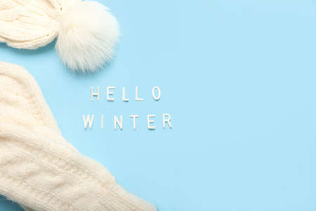 Text HELLO WINTER, knitted mittens and hat on color background, closeupの写真素材