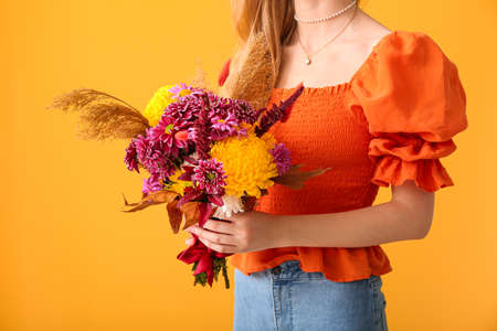 Woman with beautiful autumn bouquet on yellow background, closeupの写真素材