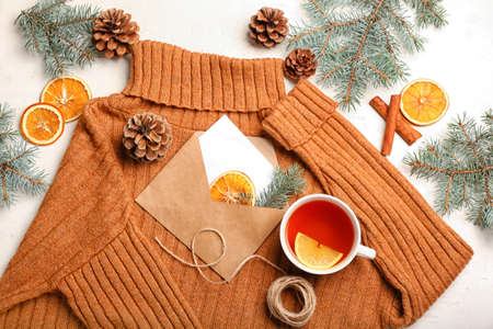 Composition with sweater, card, cup of tea, cones and fir branches on light background. hello winterの写真素材