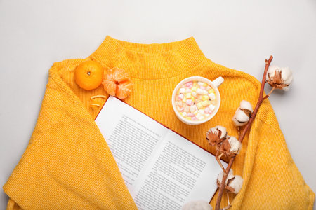 Winter composition with book, sweater, cup of cacao and tangerine on white backgroundの写真素材