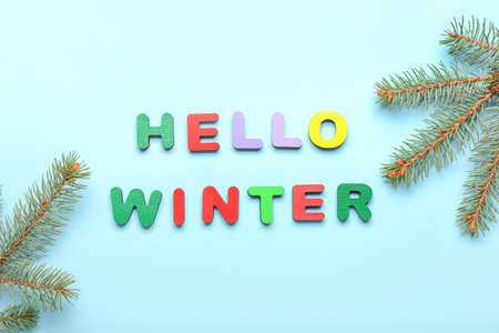 Text HELLO WINTER made of colorful letters and fir branches on blue backgroundの写真素材