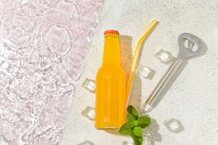 Bottle of tasty soda with mint and ice cubes in water on light backgroundの写真素材