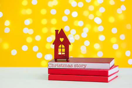 Books with glowing candle on table against blurred lights. christmas story