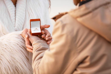 Young couple with engagement ring in box outdoors, closeupの写真素材