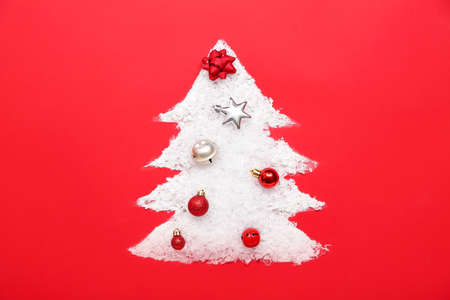 Christmas tree made of snow and decorations on color backgroundの写真素材