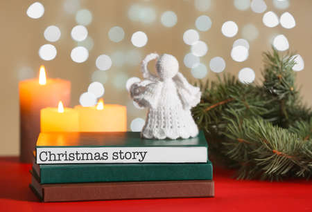 Books with angel toy on table against blurred lights. christmas storyの写真素材