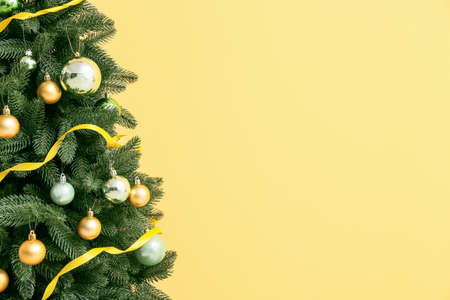 Beautiful Christmas tree with decor on yellow background, closeupの写真素材