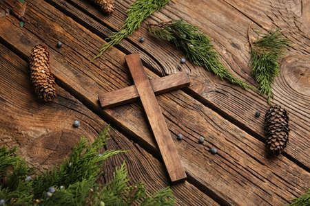 Cross with tree branches and cones on wooden background. Concept of Christmas storyの写真素材