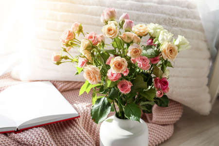 Vase with beautiful roses and soft plaid on floorの写真素材