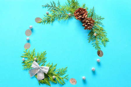 Frame made of fir branches, cones and Christmas decor on blue background