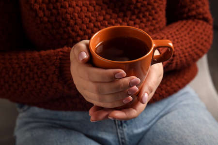 Woman drinking tasty tea in armchair, closeupの写真素材