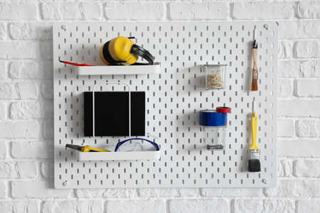 Peg board with construction tools hanging on wallの写真素材