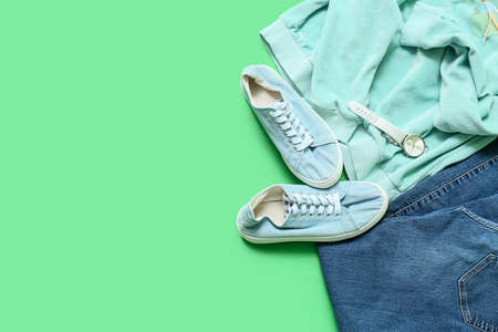 Stylish female clothes, shoes and wristwatch on color background