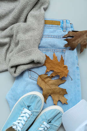 Female sweater, jeans, shoes and autumn leaves on light background, closeupの写真素材