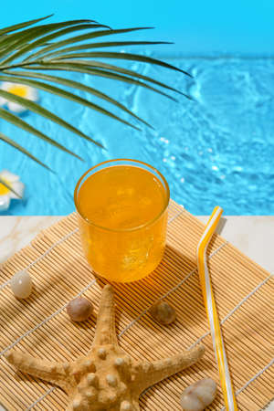 Glass of fresh soda near swimming pool